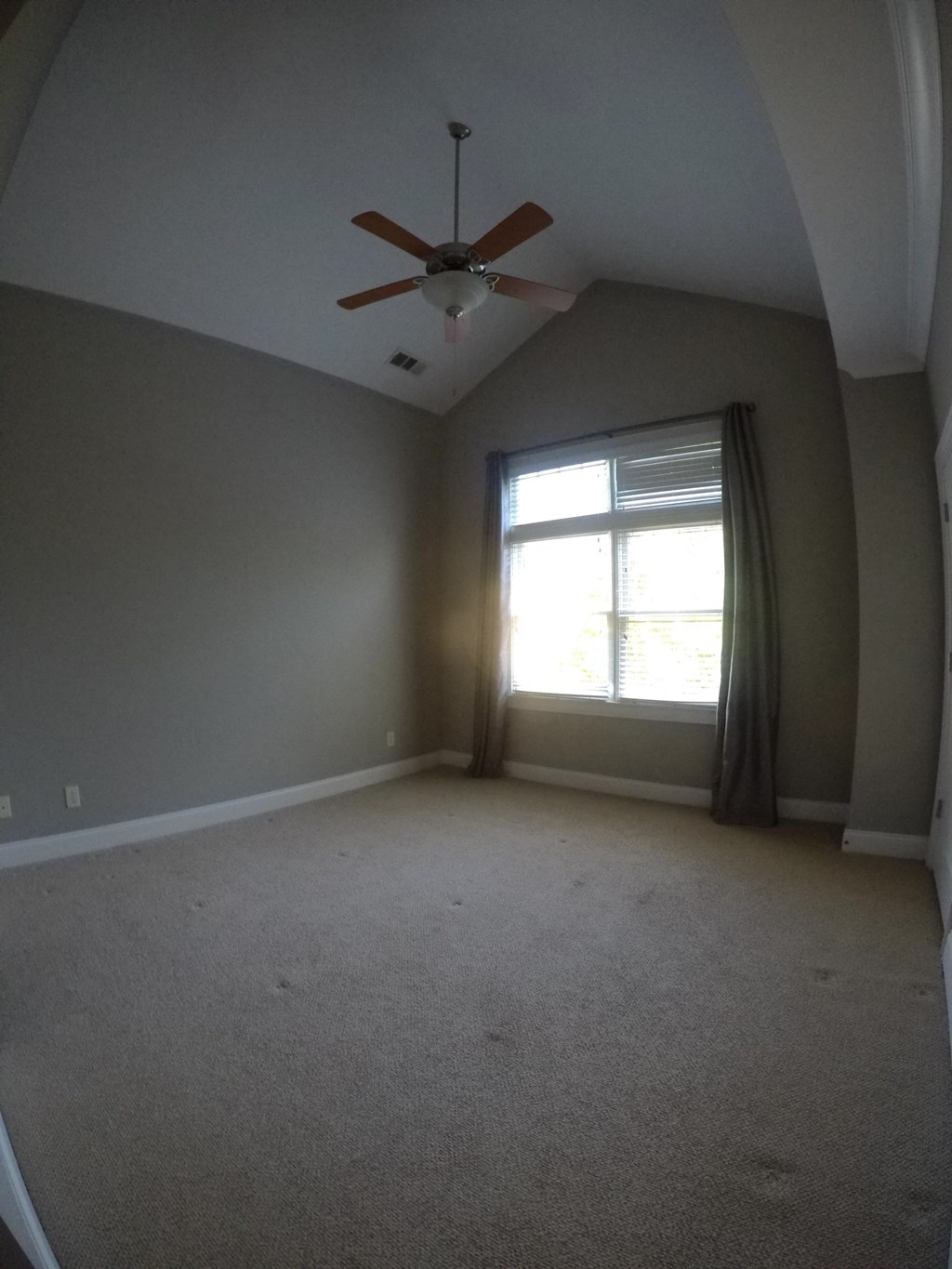an empty room with a ceiling fan and a window