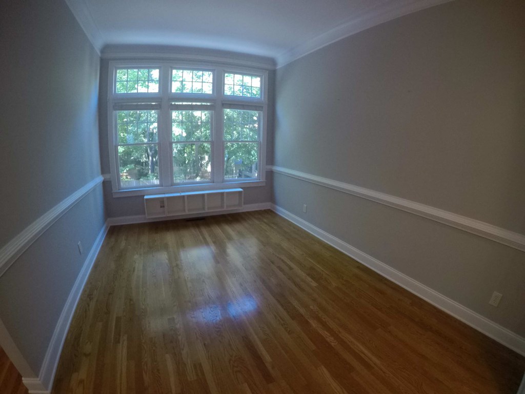 an empty room with a window and wooden floors