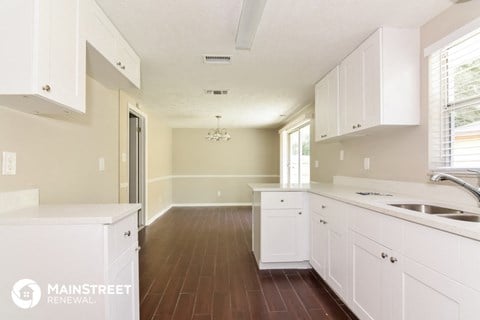 a white kitchen with white cabinets and a wooden floor