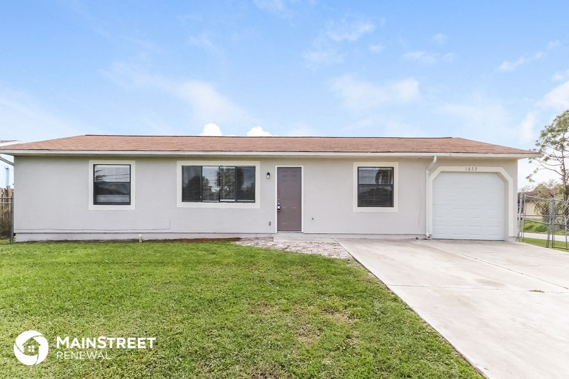 the front of a white house with a lawn and a driveway