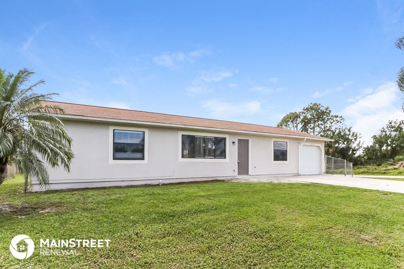 a white house with a lawn and a palm tree