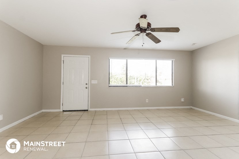 an empty living room with a ceiling fan and a window