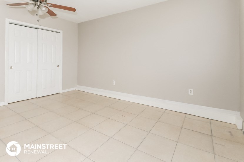 the living room of an empty room with a ceiling fan