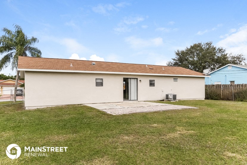 a small white house with a yard and a blue house