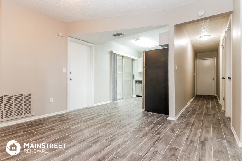 the living room and hallway of an apartment with wood flooring