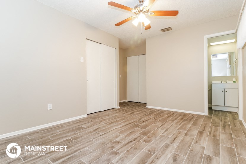 the spacious living room with hardwood flooring and a ceiling fan