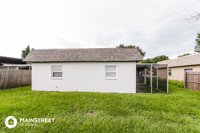 the backyard of a small white house with a chicken coop