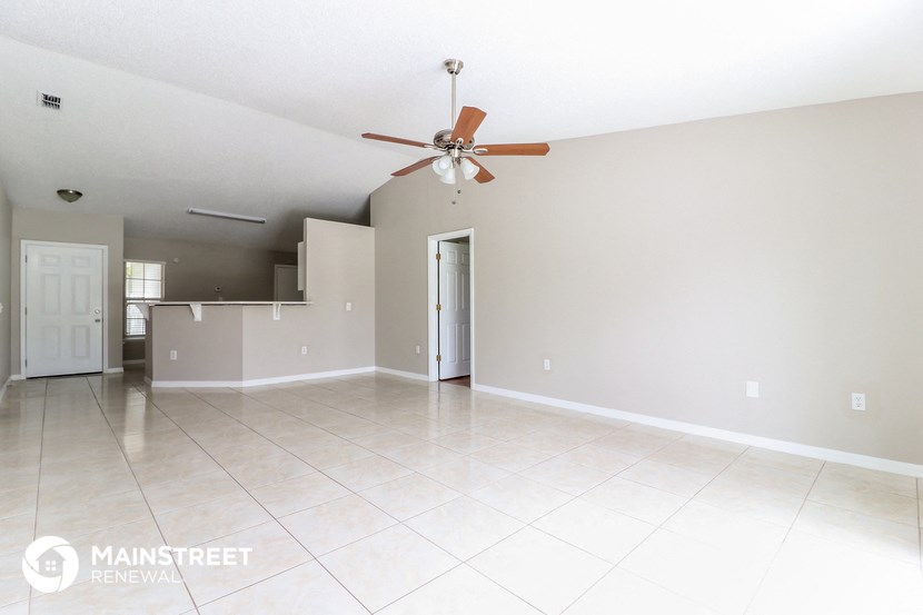 an empty living room and kitchen with a ceiling fan
