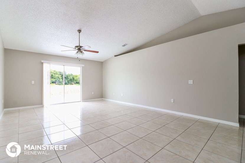 a spacious living room with tile flooring and a ceiling fan