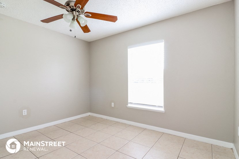 an empty room with a ceiling fan and a window
