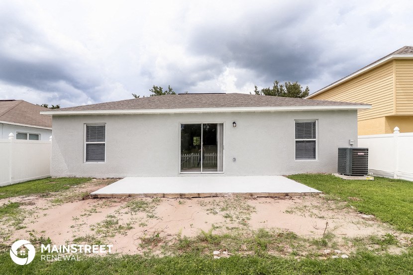 the front of a white house with a yard with dirt