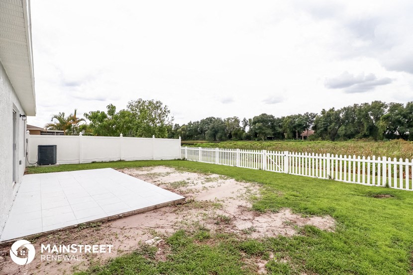 a backyard with a white fence and a lawn and a white gate