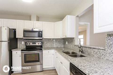 an updated kitchen with granite counter tops and white cabinets