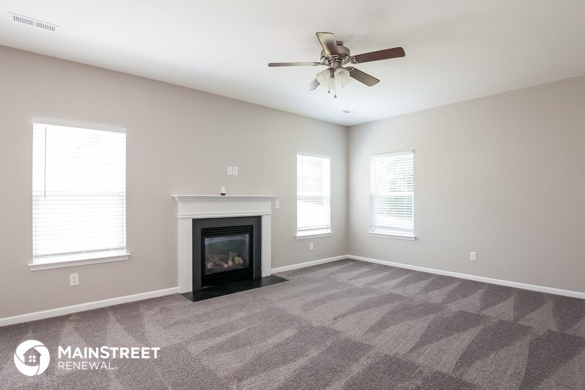 the living room with fireplace and ceiling fan