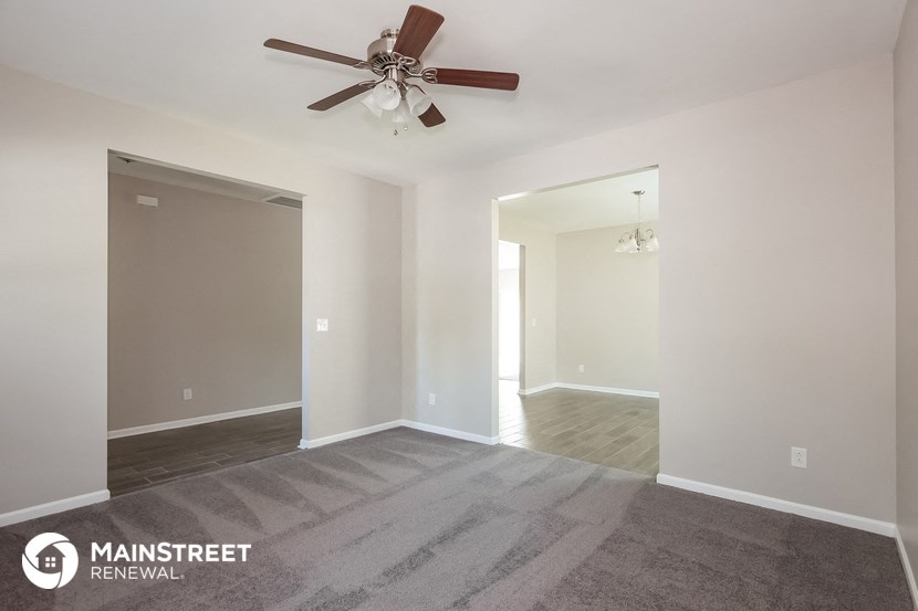 a living room with a ceiling fan and a door to a hallway