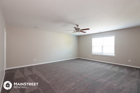 the spacious living room with carpet and ceiling fan