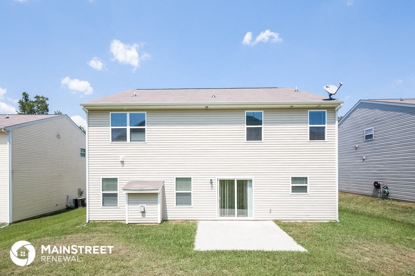 side view of a white house with white siding and green grass