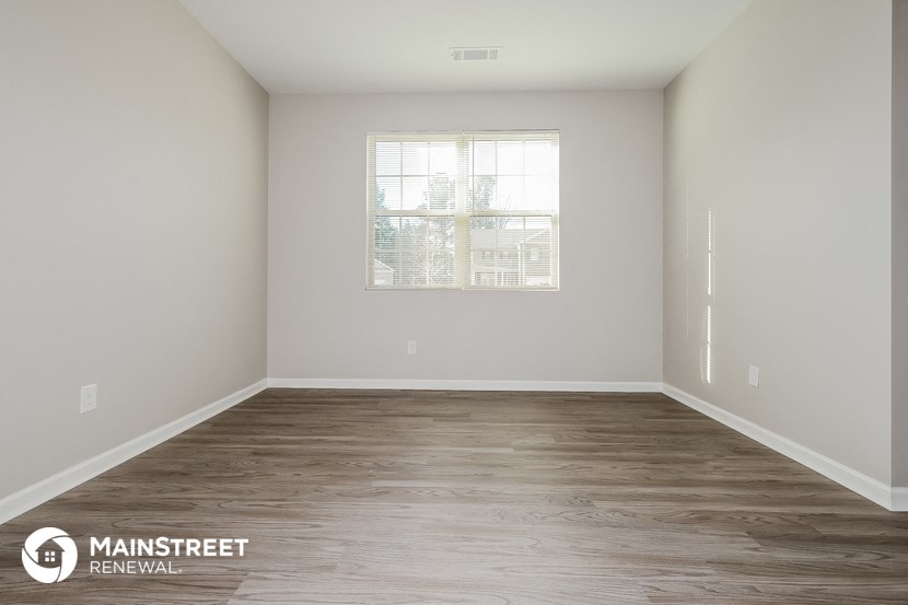 an empty room with wood floors and a window