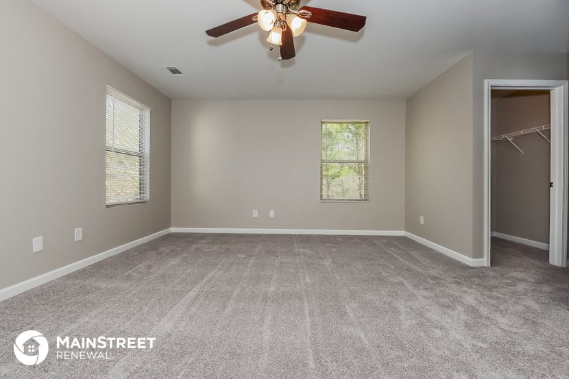 the master bedroom with carpeted flooring and a ceiling fan