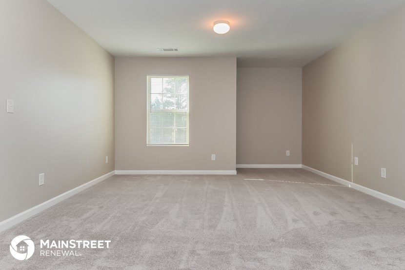 the spacious living room with carpeted flooring and window