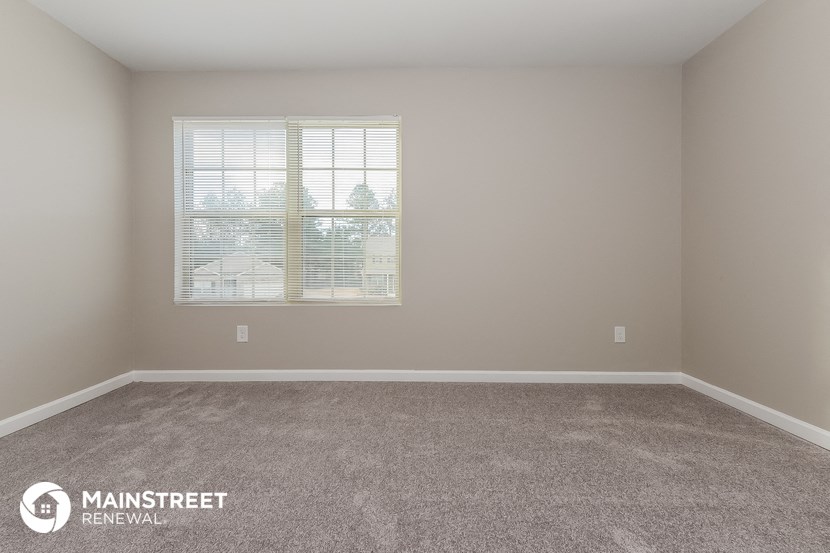 an empty room with a window and carpet