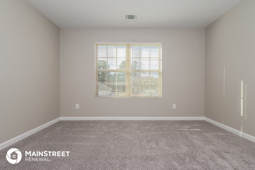 a spacious room with carpet and a window