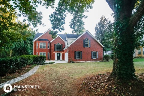 a large brick house with a yard and a tree