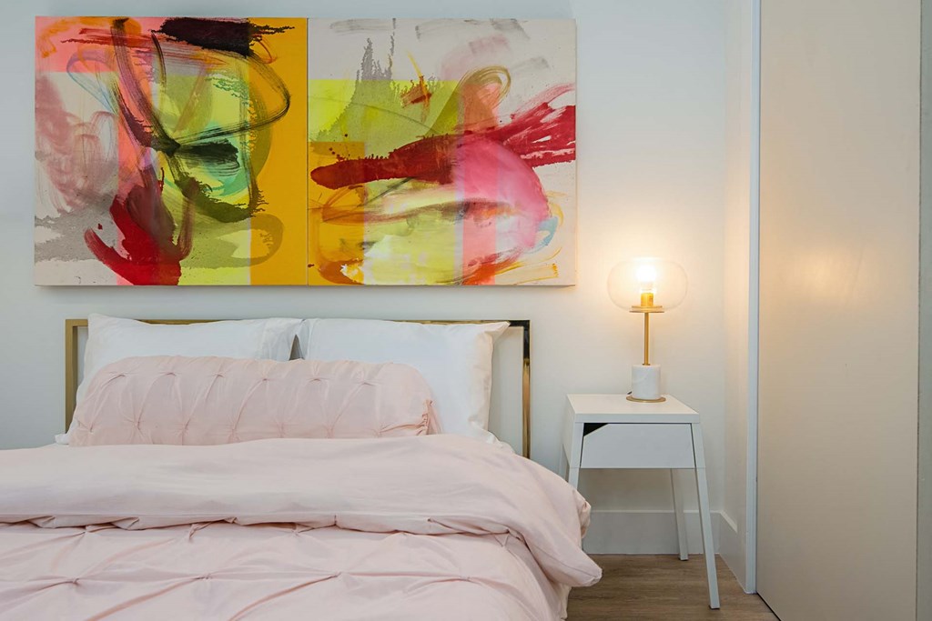 a bedroom with a bed and two paintings on the wall