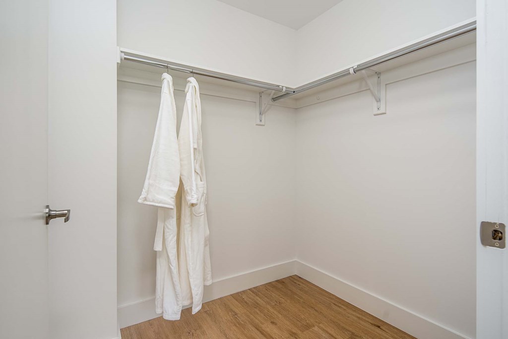 a room with white walls and a closet with two white towels hanging on the wall