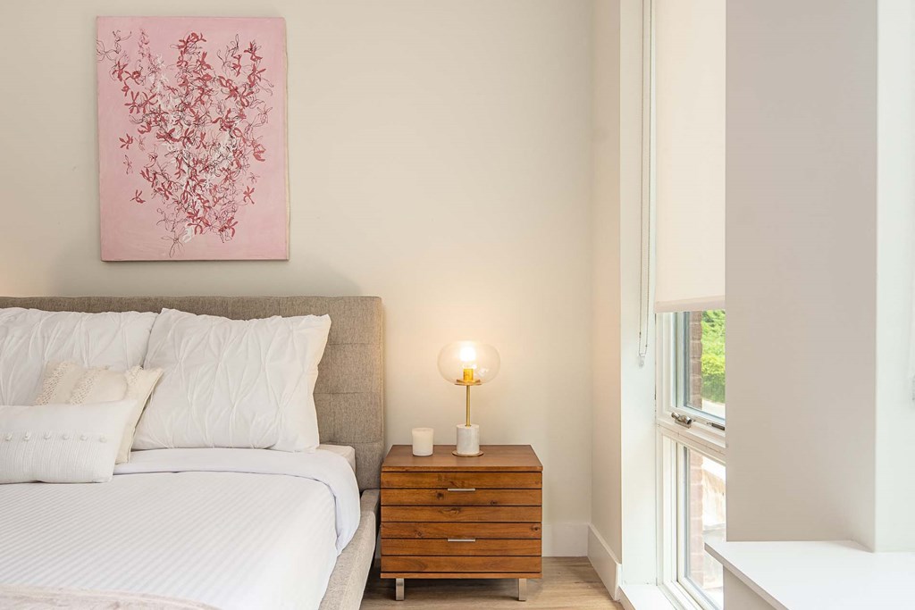 a bedroom with a bed and a pink painting on the wall