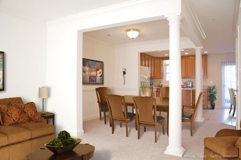 A living room with a brown couch and a painting on the wall.