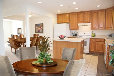 A kitchen with wooden cabinets and a dining table with chairs.