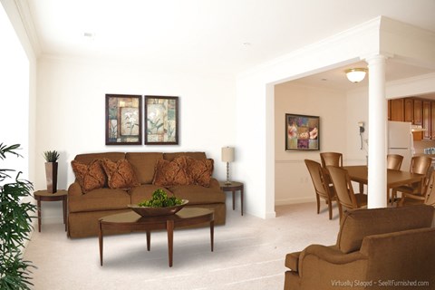 A living room with a brown couch and a table with a plant on it.