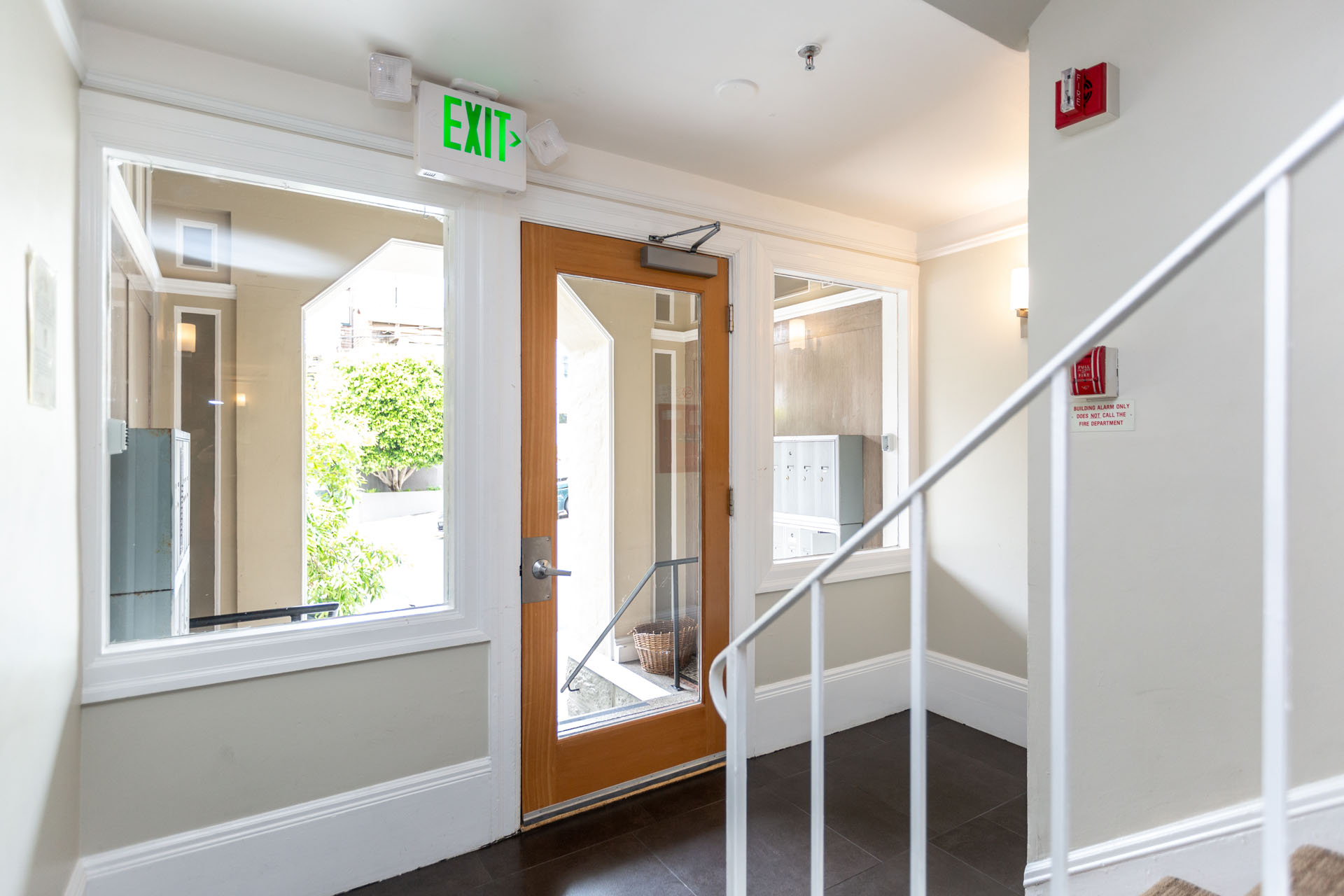 A hallway with a white railing and a green exit sign.