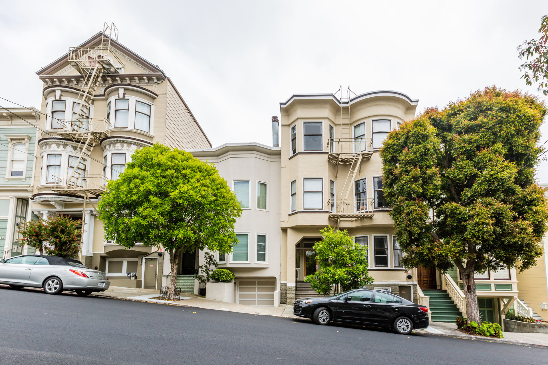 A black car is parked in front of a two-story house.
