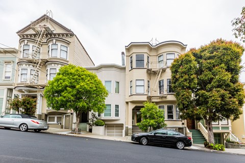 A black car is parked in front of a two-story house.