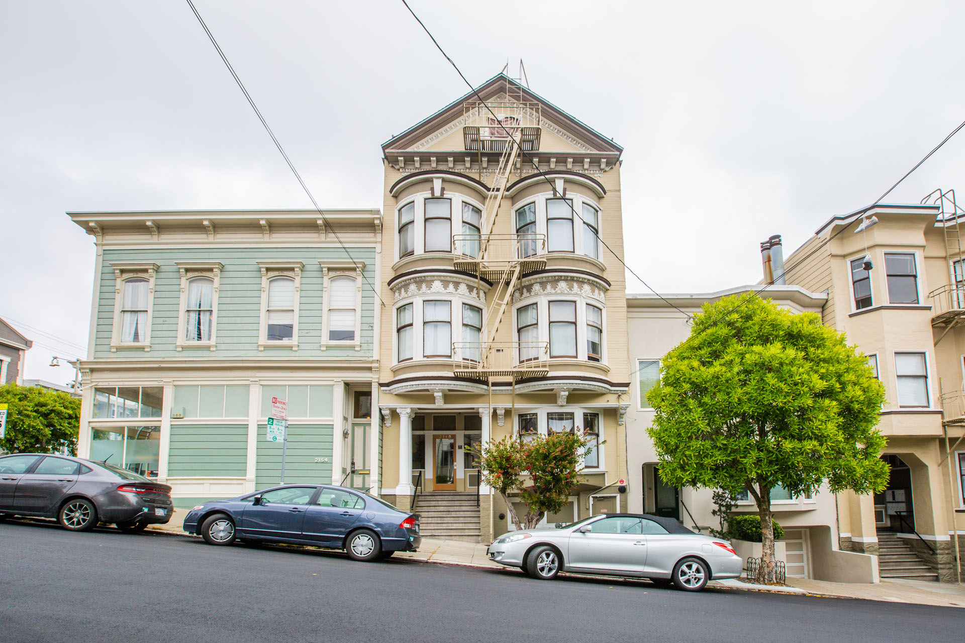 A row of houses with cars parked in front.