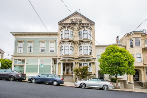 A row of houses with cars parked in front.