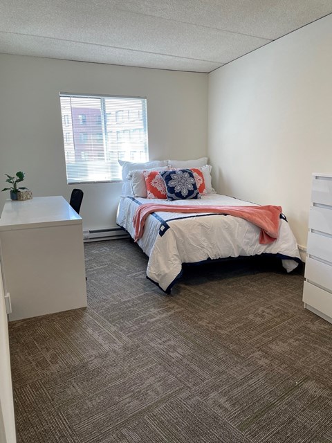 A bedroom with a bed, desk, and chair.