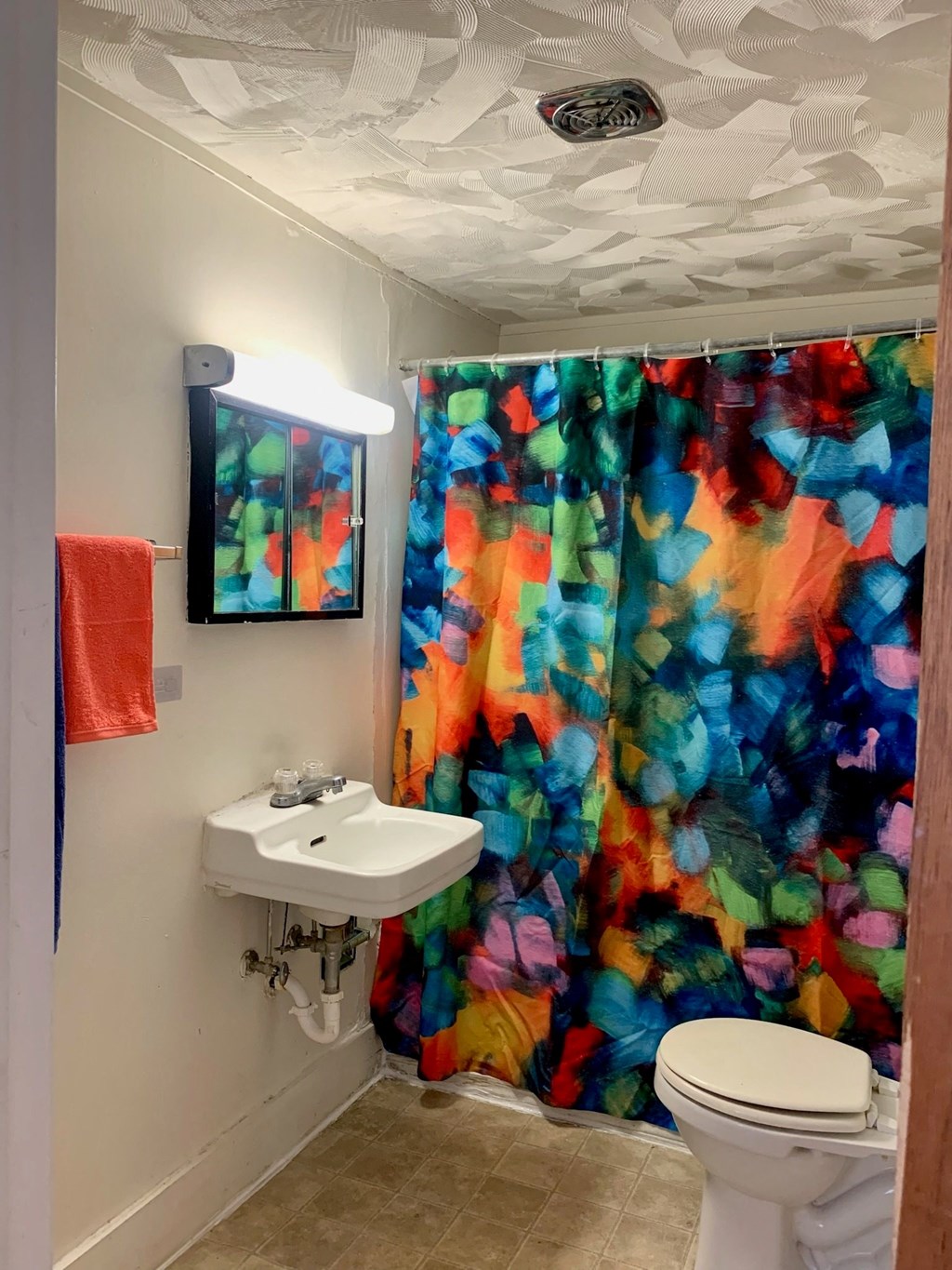 A bathroom with a white sink and a colorful shower curtain.