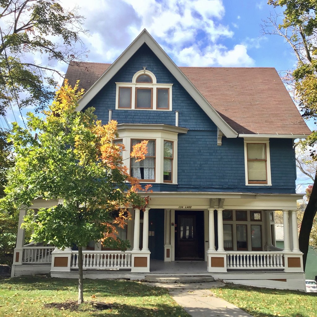 A blue house with white trim and a brown roof.