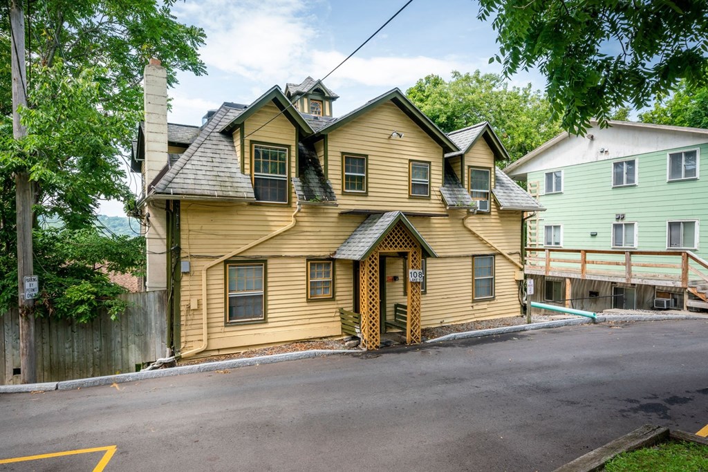 A yellow house with a black roof and a brown door.