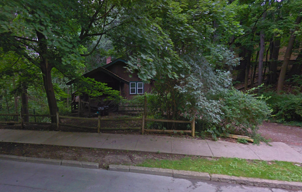 a house in the woods behind a wooden fence