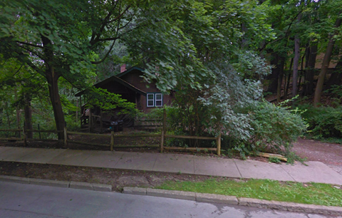 a house in the woods behind a wooden fence