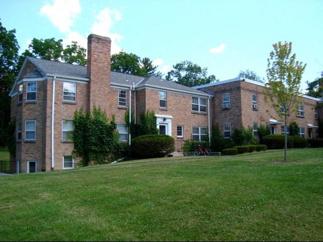 a large brick apartment building with a green lawn