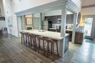 a kitchen with an island and bar stools in a living room