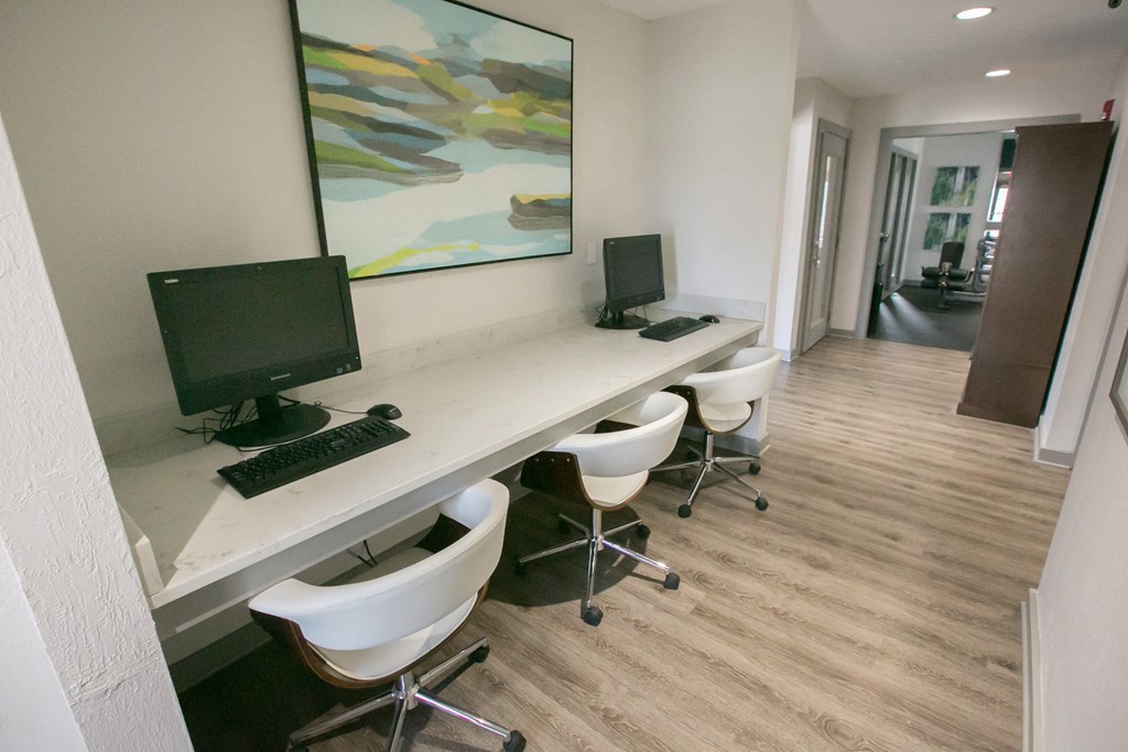 a room with a long desk with computer monitors and chairs