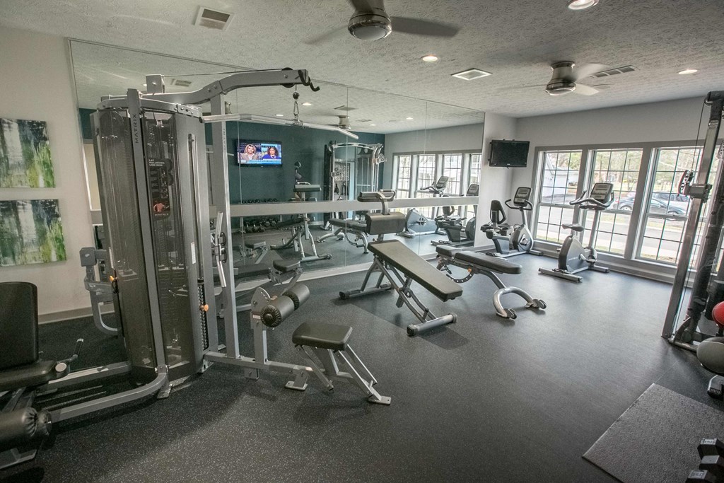 a gym with weights and cardio equipment in a room with windows
