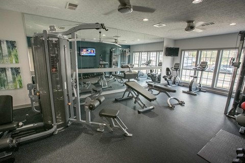 a gym with weights and cardio equipment in a room with windows