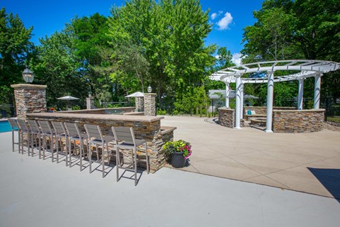 a large patio with chairs and a bar and a pool